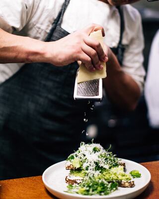 Server grates cheese over fresh green salad