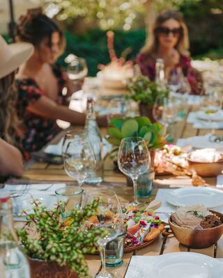 women at table with wine glasses and flowers in vases