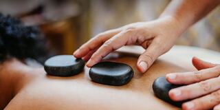 Spa Therapist Using Hands to do a Stone Treatment on a Woman's Back
