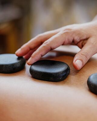 Spa Therapist Using Hands to do a Stone Treatment on a Woman's Back