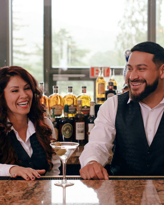 Two bartenders smiling at a bar