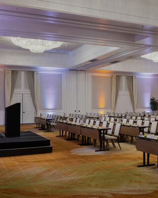 Room set up for a group or conference with long tables and chairs and a podium