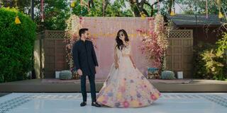 Husband and wife both wearing sunglasses standing in front of a stage in an outdoor setting