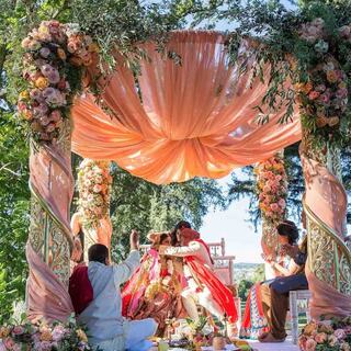 Traditional mandap with the bride and groom embracing each other next to family
