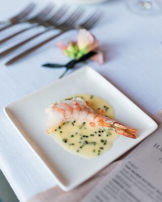 Fancy plated food on a table with flowers and silverware