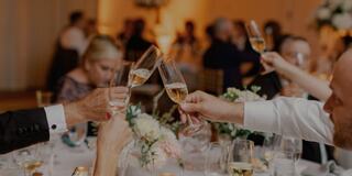 People sitting at a table cheersing with champagne flutes for a wedding reception