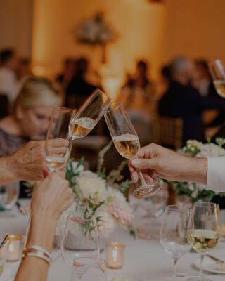 People sitting at a table cheersing with champagne flutes for a wedding reception