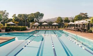 Lap pool with umbrellas and trees and hills in the background