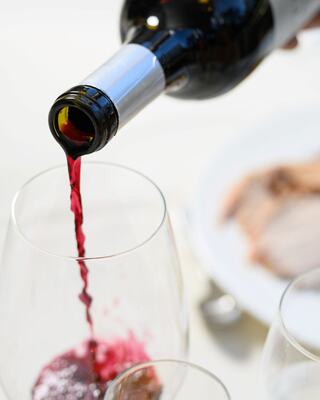 Wine bottle pouring red wine into a wine glass