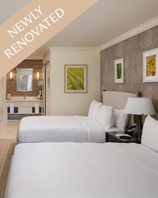 Two queen hotel beds with art on the walls