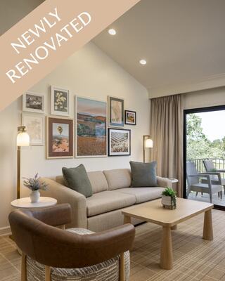 A Living Room in a Hotel Suite with Dining Furniture, a Mounted TV, Lamps, a Decorative Vase, and Door to an Outdoor Patio