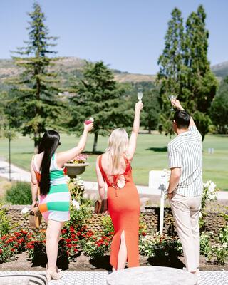 Three young adults holding their cocktails in the air overlooking the golf course in Napa at Silverado Resort