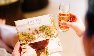 person holding a spa brochure and champagne