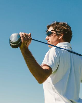 A Man Holding his Golf Club Looking into the Distance Outside
