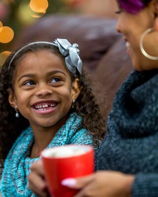 Daughter smiling at Mother with holding coco