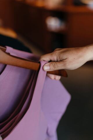 A shirt on a hanger wit ha hand taking it off the rack
