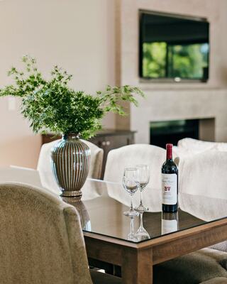 A Dining Room with a Mounted TV, Furniture, and a Bottle of Wine with Wine Glasses