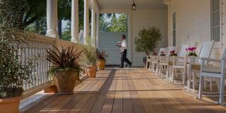 Person walking with tray of wine glasses on porch