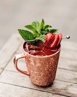 Cocktail in a Copper Cup Topped with Strawberries and Mint Leaves