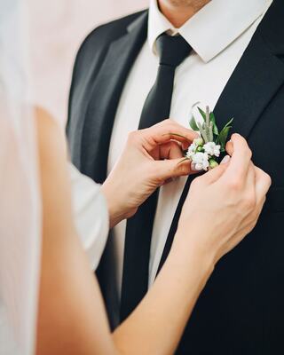Woman Pining a Decorative Flower to a Suit for a Wedding