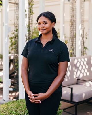 Woman Staff Member in Branded Silverado Shirt Standing Outside with Her Hands Gently Folded