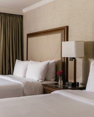 Hotel Room with Two Beds, a Lamp, and a Vase with Flowers in it in Napa