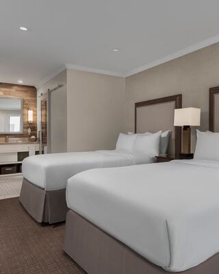 Hotel Room with Two Beds, Furniture, and a Bathroom Vanity in Napa