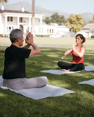 Two People Doing a Yoga Meditation Pose Outside on the Lawn in Front of a Mansion in Napa