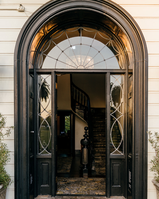 Arched Glass Mansion Door with a View to the Inside Curved Staircase
