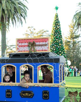 Family riding the Santa Train with Christmas Tree in Background
